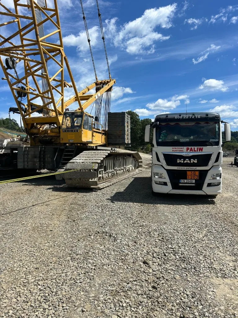 Autocysterna MAN M-TRANS na placu budowy obok dźwigu Liebherr